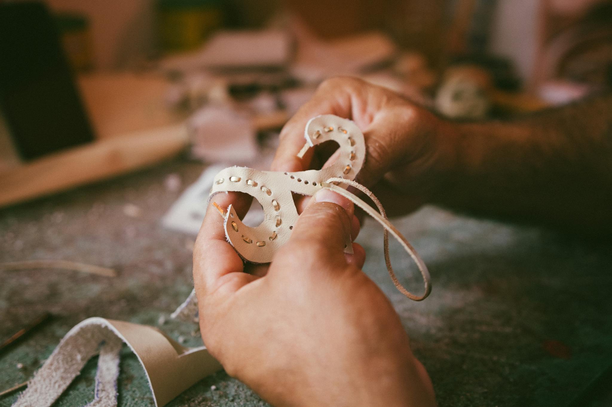 A skilled artisan crafting a leather bracelet with precision and care in a workshop.