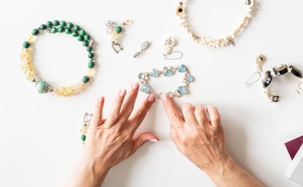 Top view middle aged woman hands working on jewels on white table
