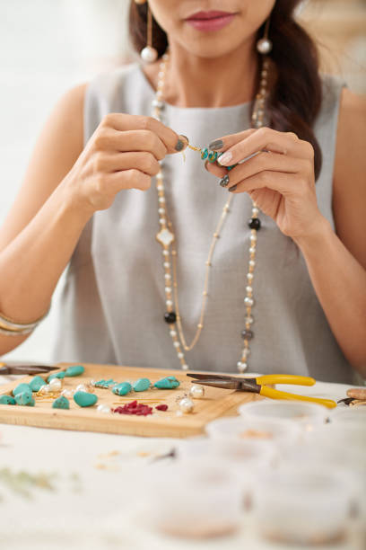 Cropped image of woman making earrings with gemstones
