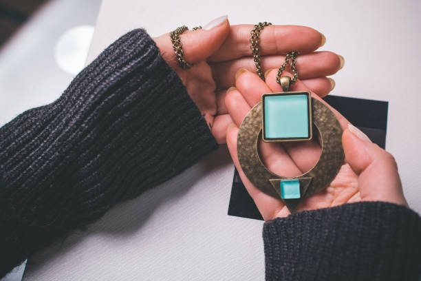 Woman holding fashionable necklace in hands. viewers perspective